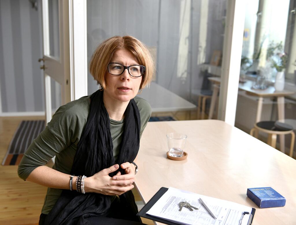 Psykologen Linda Gjertsson sitter vid ett skrivbord och pratar med en person som inte syns på bilden